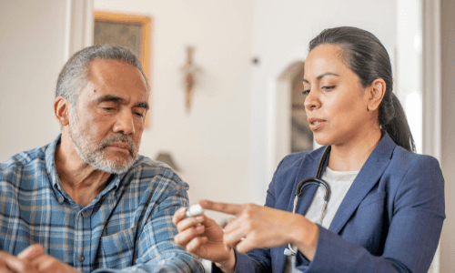 Diverse female health care professional showing middle-aged male patient how to use CGM