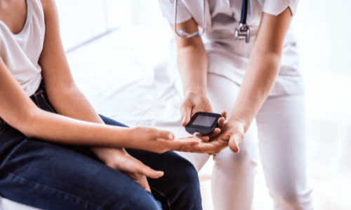 Close-up of female health care practitioner helping female patient test her glucose level