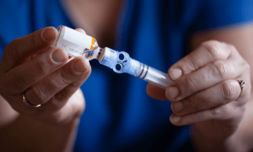 Close-up of a woman's hands loading insulin into an insulin pump