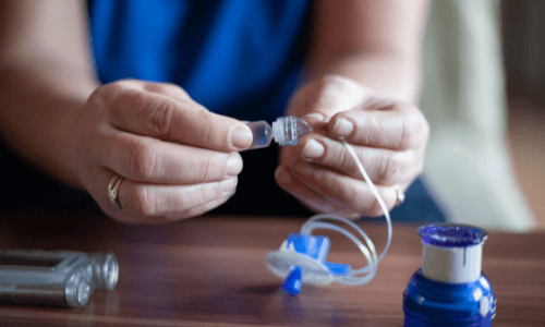 Close-up of a woman's hands over a table preparing an insulin pump for use