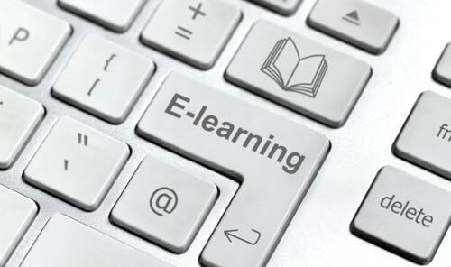 Close-up of white computer keyboard with E-learning typed on the Enter key & an open book icon on the key above it