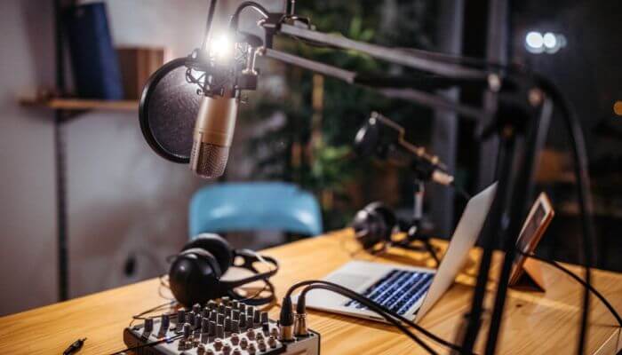 Wooden desk with laptop, headset, microphones & control board on it