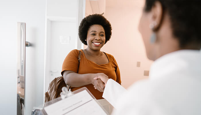 Female health care professional shaking hands with a female patient