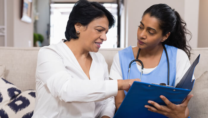 Female patient reviewing a file & speaking to a female health care professional about it