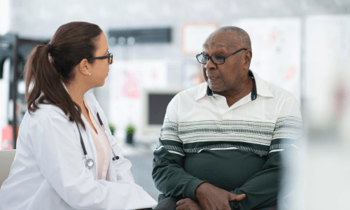 Side view of a female health care professional listening to a diverse adult male patient